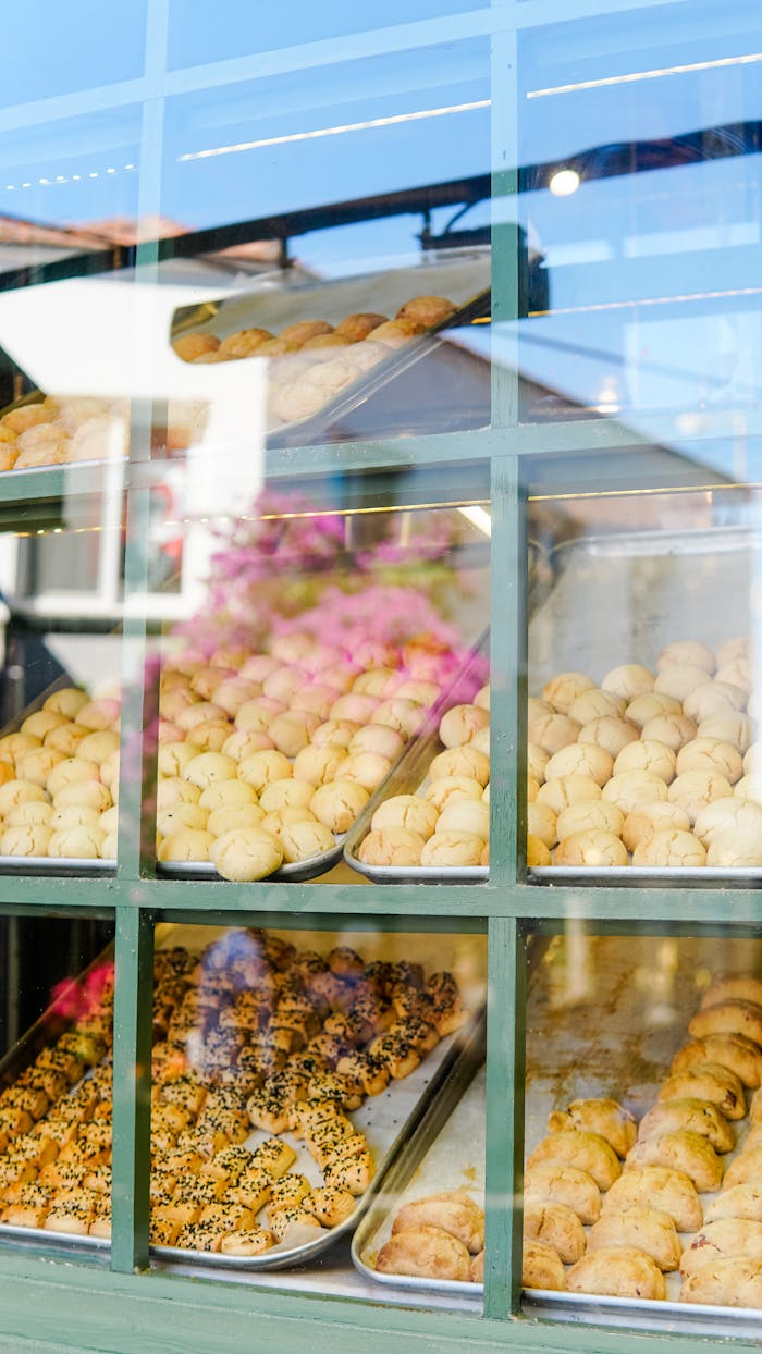 who-we-are Freshly baked goods displayed in a bakery window in Alaçatı, İzmir, showcasing a variety of pastries and buns.